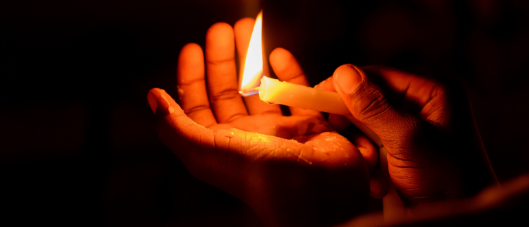 Hands around a burning candle