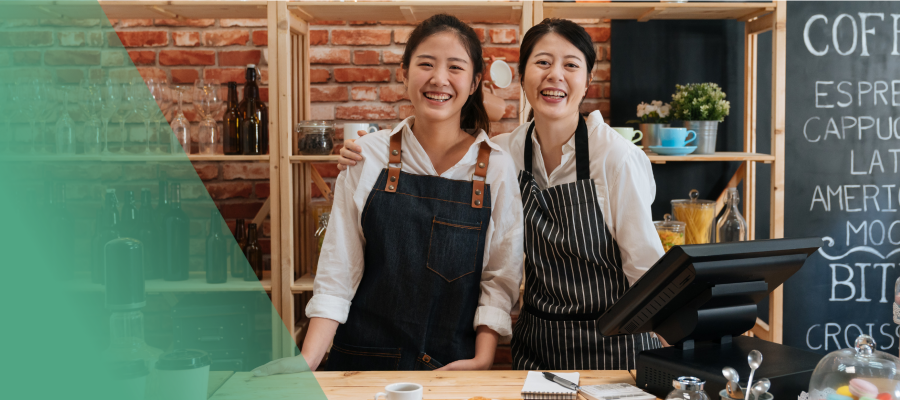 two women in aprons, smiling at the camera