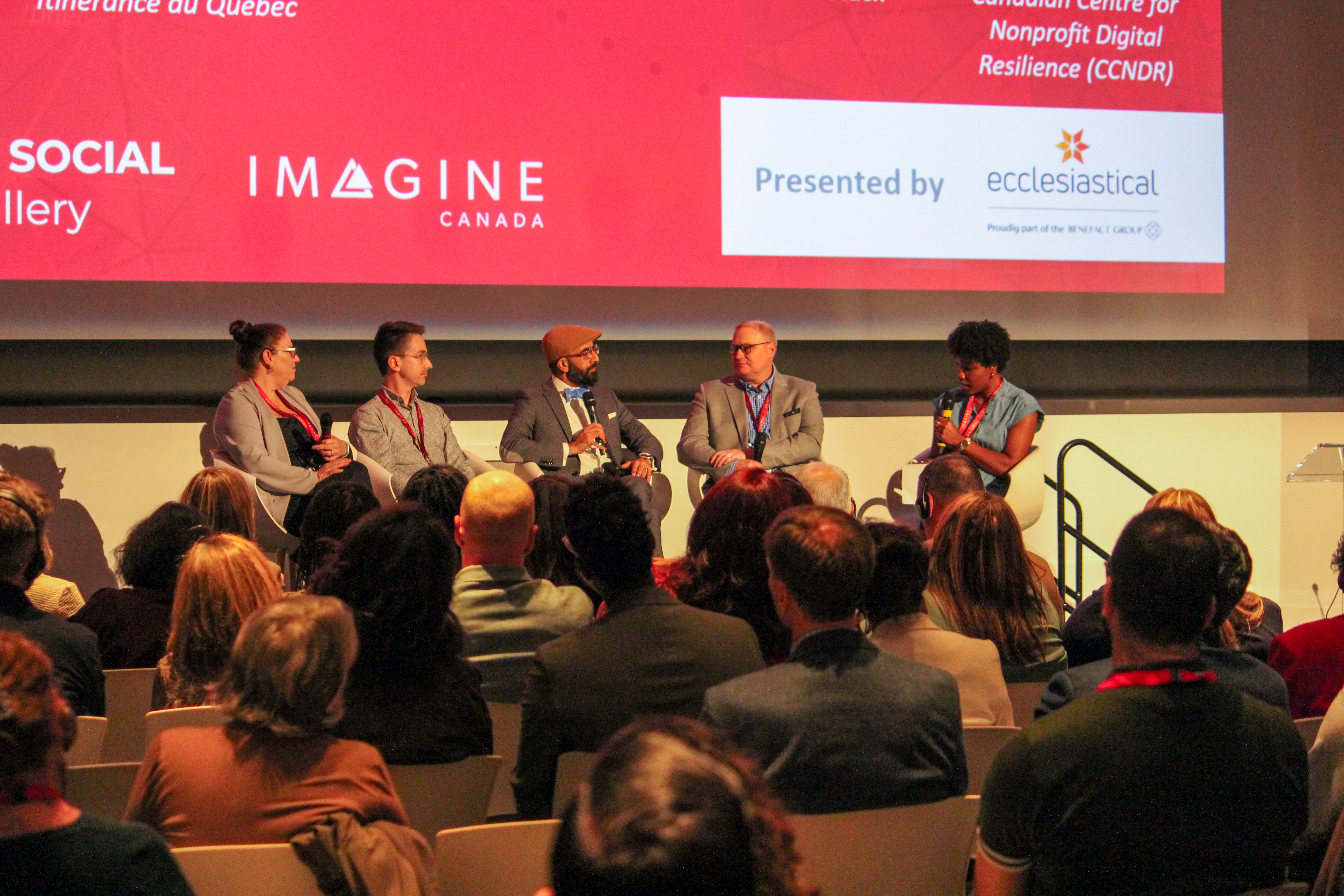 Cinq panélistes s’expriment sur scène devant un public assis lors d’un événement Sector Social 2025, avec un écran rouge vif en arrière-plan.