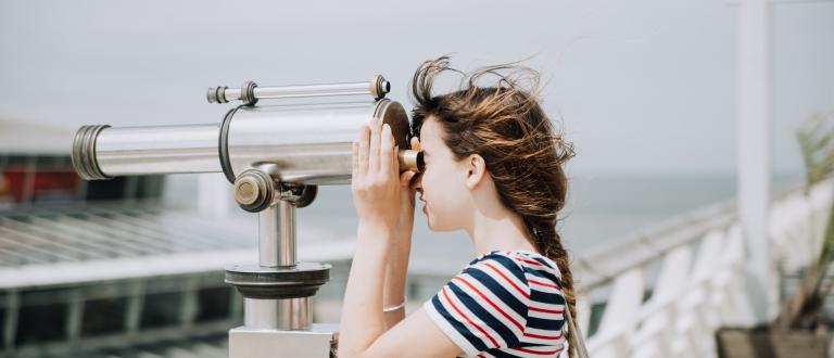 girl looking through large binoculars 