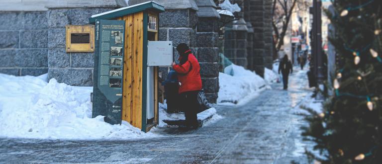 Une personne qui vérifie un frigo solidaire en hiver