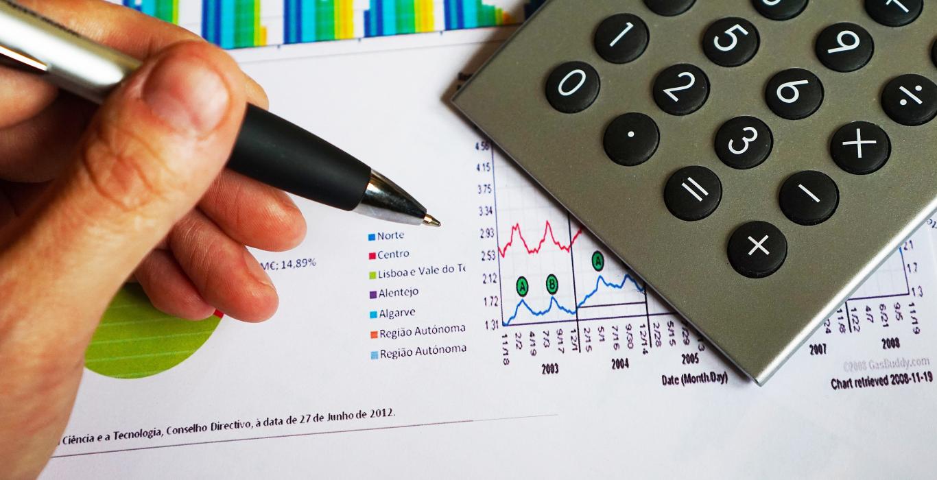 L'image montre la main avec un stylo, une calculatrice et un rapport imprimé