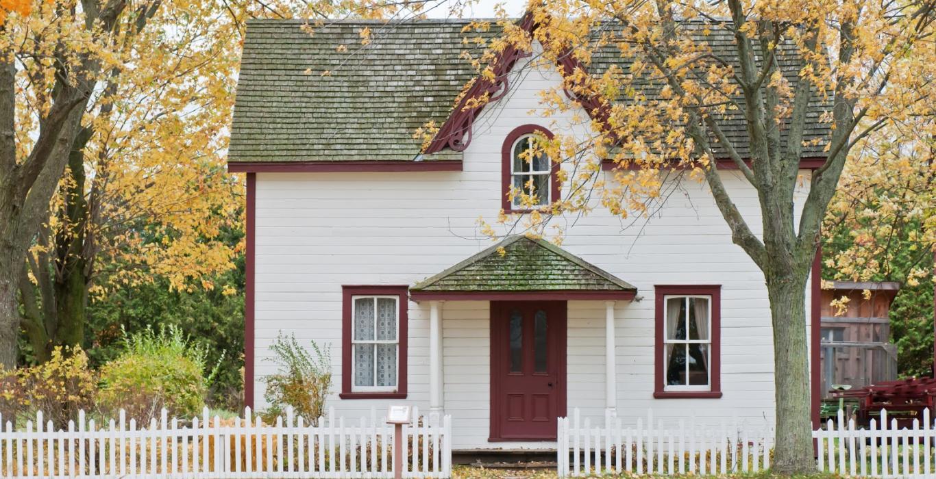 White house with cedar roofing and white picket fence