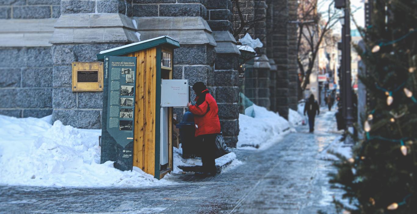 Une personne qui vérifie un frigo solidaire en hiver
